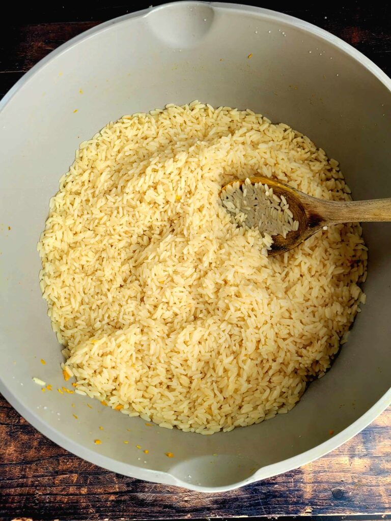 cooked rice in a large pots with a wooden spoon