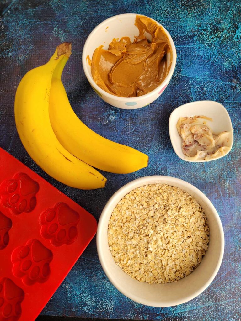 a picture of all the ingredients needed to make homemade dog biscuits like peanut butter, banana and oats.