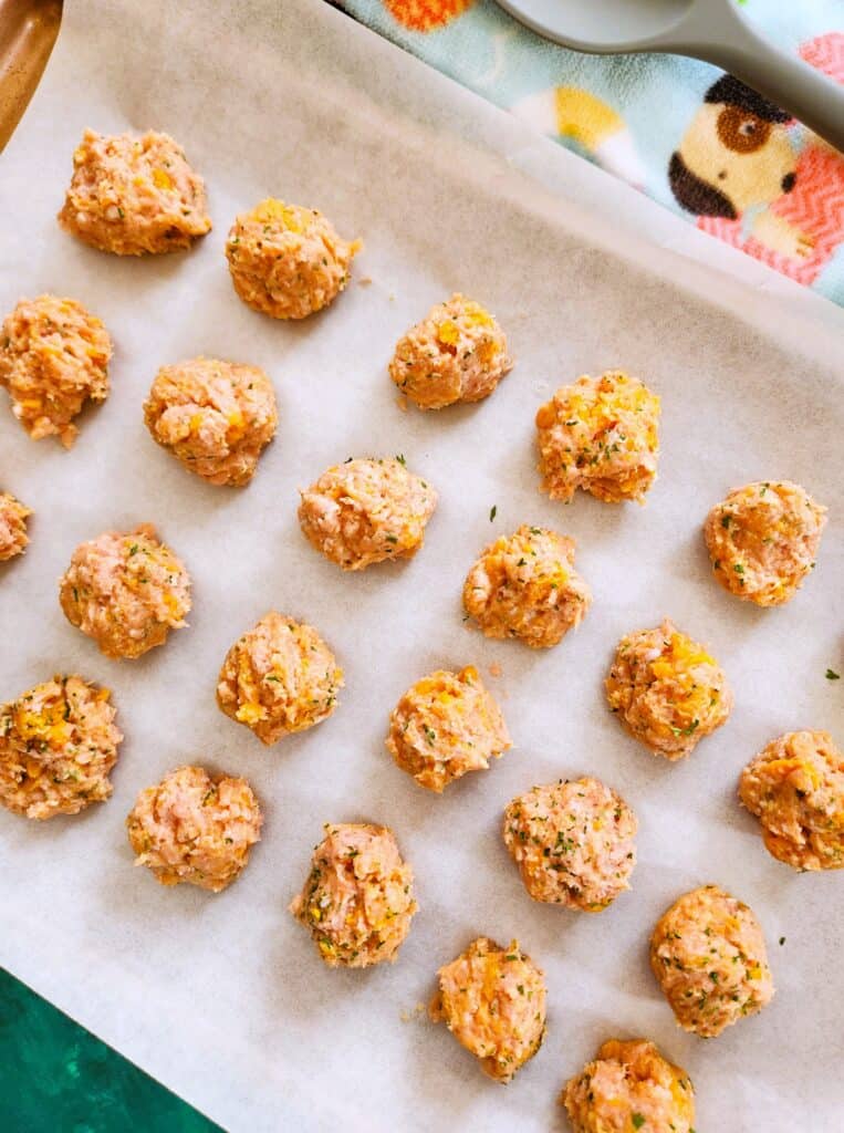 Turkey sweet potato dog meatballs spaced on a parchment-lined baking sheet ready to bake
