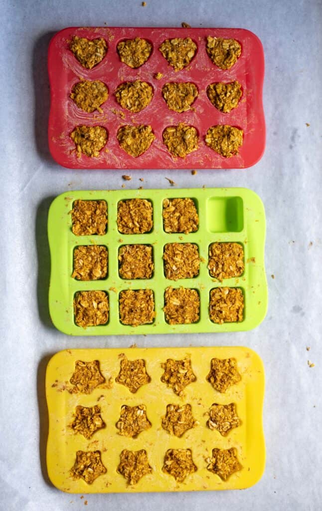 Pressing pumpkin dog treat mixture into silicone molds to shape calming chews for dogs